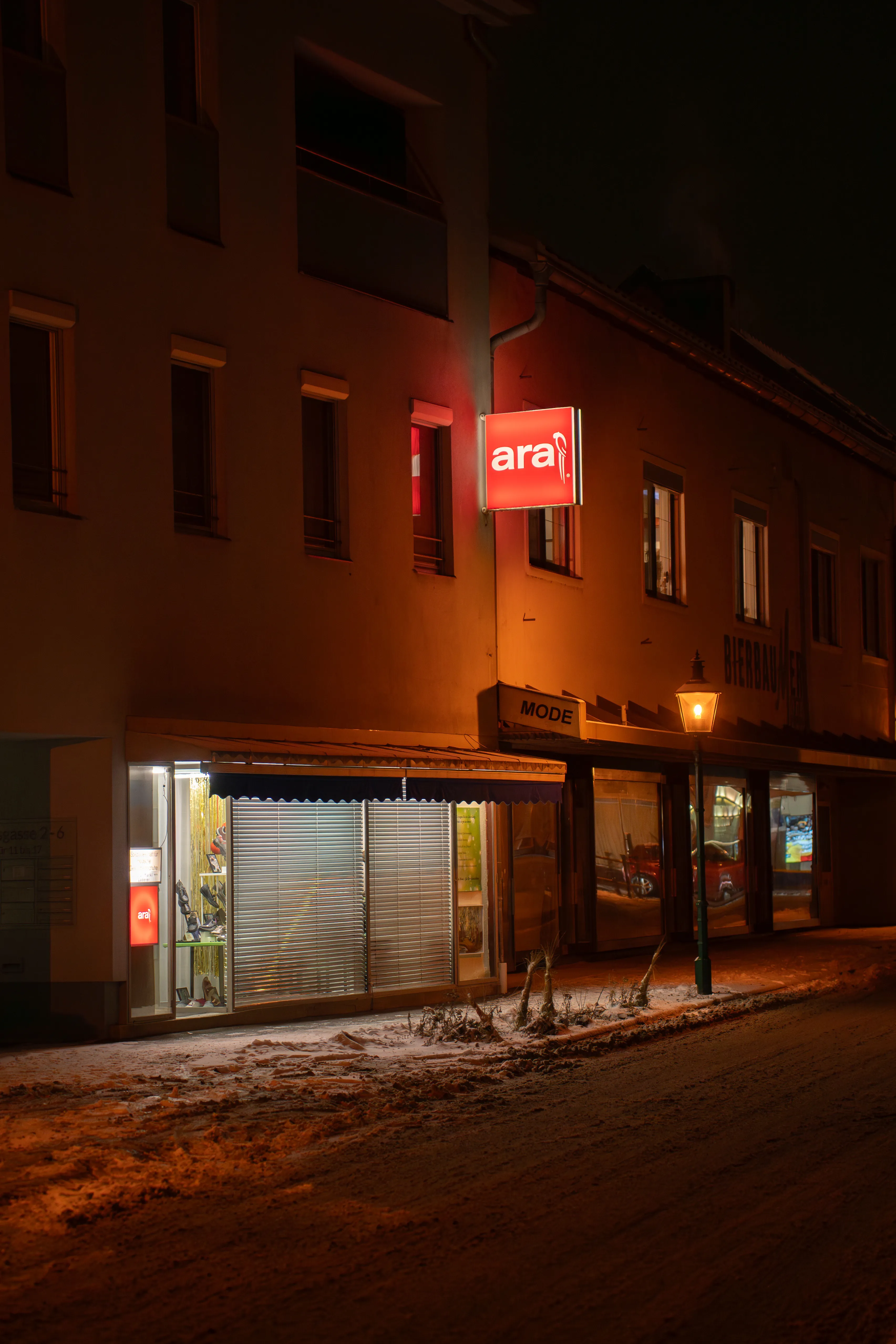 a store with a glowing red sign above it, photographed at nighttime
